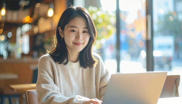 カフェでノートパソコンを使う日本人女性 カフェでノートパソコンを使う日本人女性の写真