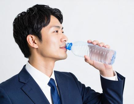 ペットボトルの水を飲むビジネスマン ペットボトルの水を飲むビジネスマンの写真