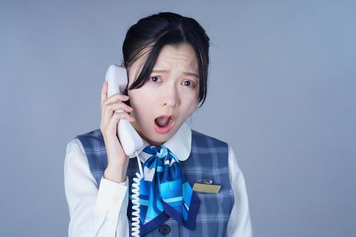 電話で困った顔の青いリボンの制服の女性 女性,困る,怒るの写真素材