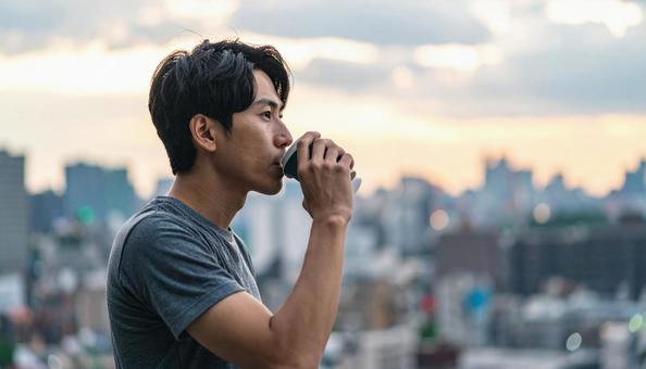 屋上でコーヒーと電子タバコを嗜む男性 屋上でコーヒーと電子タバコを嗜む男性の写真