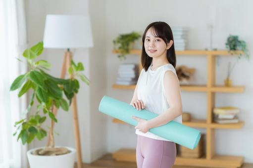 リビングでヨガをする若い女性 リビングでヨガをする若い女性 トレーニング,ヨガマット,持つの写真素材