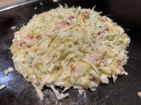 焼き始めのお好み焼き(アップ)の写真