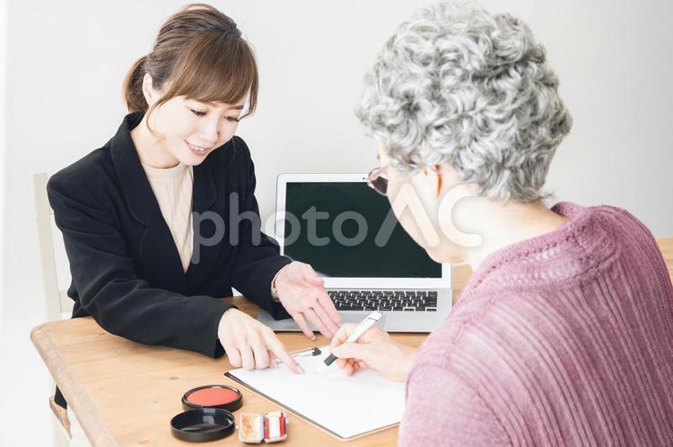 スーツ姿の女性と書類にサインする高齢者 高齢者,終活,遺言書の写真素材