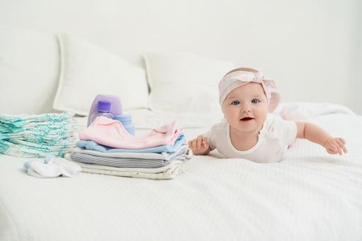 ベビー用品と笑顔でカメラ目線の腹ばいの赤ちゃん ベビー用品と笑顔でカメラ目線の腹ばいの赤ちゃん 赤ちゃん,かわいい,ベビーヘアバンドの写真素材