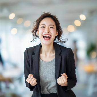 笑顔でガッツポーズするビジネスウーマンの写真