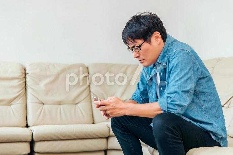 ソファに座る男性 スマホ,男性,携帯電話の写真素材