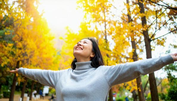 紅葉の中で深呼吸する秋服の日本人女性 紅葉の中で深呼吸する秋服の日本人女性の写真