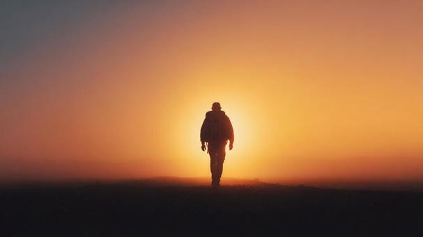 夕日に向かって歩く男性 夕日に向かって歩く男性の写真
