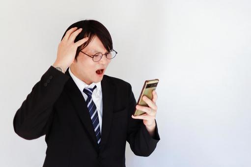 スマホを見て驚く男性 スマホを見て驚く男性 男性,ビジネスマン,スーツの写真素材