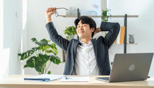 仕事が終わり達成感で背伸びをする社員の写真