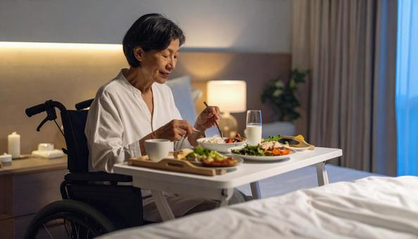 病室で車いすに座り食事をする高齢女性患者 病室で車いすに座り食事をする高齢女性患者の写真