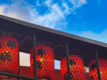 Red lanterns and the word "Kushiyaki" (grilled skewers) stand out against the blue sky, JPG Red lanterns and the word "Kushiyaki" (grilled skewers) stand out against the blue sky, JPG