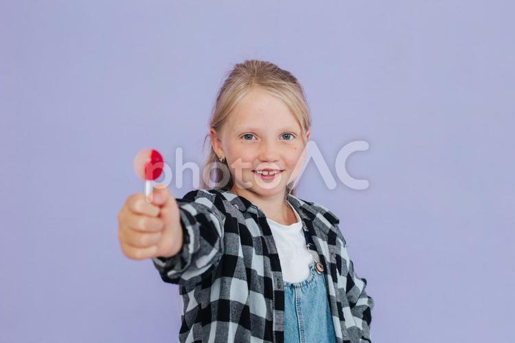 キャンディーを待ちカメラ目線で笑う女の子 女の子,キャンディー,持つの写真素材