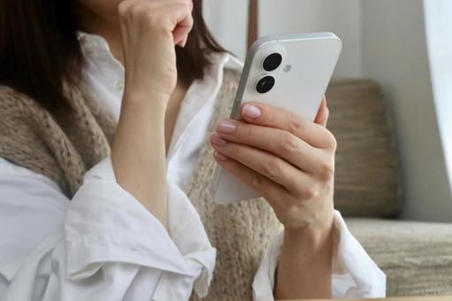 スマホを見ながら考える女性 スマホ,女性,考えるの写真素材