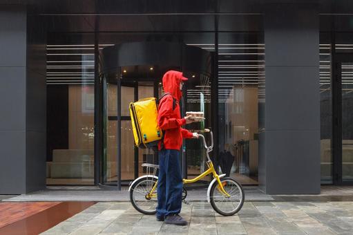 ドリンクを手に持って自転車を押すフードデリバリーの男性 配達,デリバリー,配送の写真素材