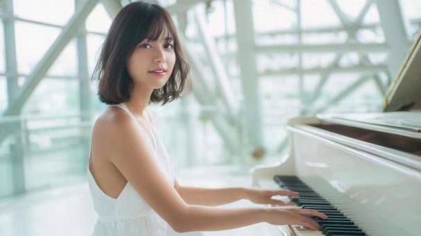 白いドレスを着てピアノを弾く笑顔の女性の写真