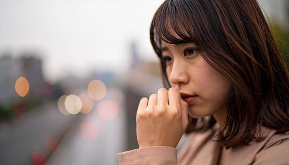 困った顔で手を顎に当てる若い女性 困った顔で手を顎に当てる若い女性の写真
