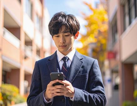 スマホを操作する男子高校生の写真