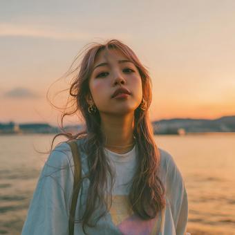夕焼けのビーチで物憂げな表情の日本人女性 夕焼けのビーチで物憂げな表情の日本人女性の写真