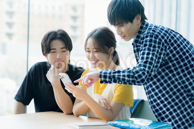 スマホを見ながら話す学生たち 大学生,スマホ,教室の写真素材