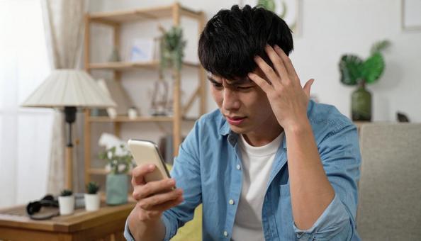 スマホを見て困惑する男性のリアクション スマホを見て困惑する男性のリアクションの写真