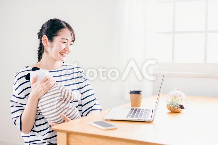 赤ちゃんを抱きながらテレワークする女性 副業,ママ,保育の写真素材