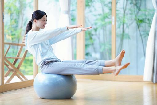 ボールに座り手足を伸ばす女性 女性,バランスボール,座るの写真素材