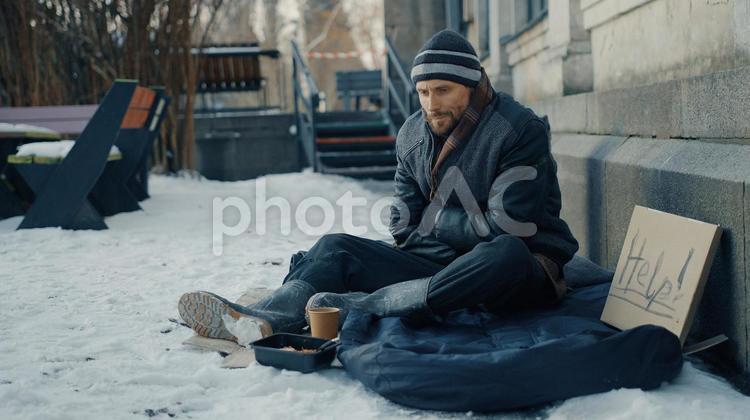 助けを求めて炊き出しを食べるホームレスの男性 男性,ニット帽,ヒゲの写真素材