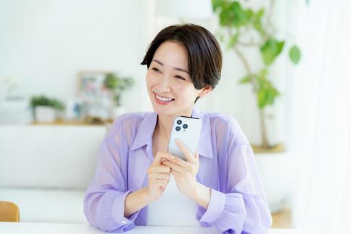 部屋でスマホを操作するミドル女性 部屋でスマホを操作するミドル女性 スマホ,笑顔,女性の写真素材
