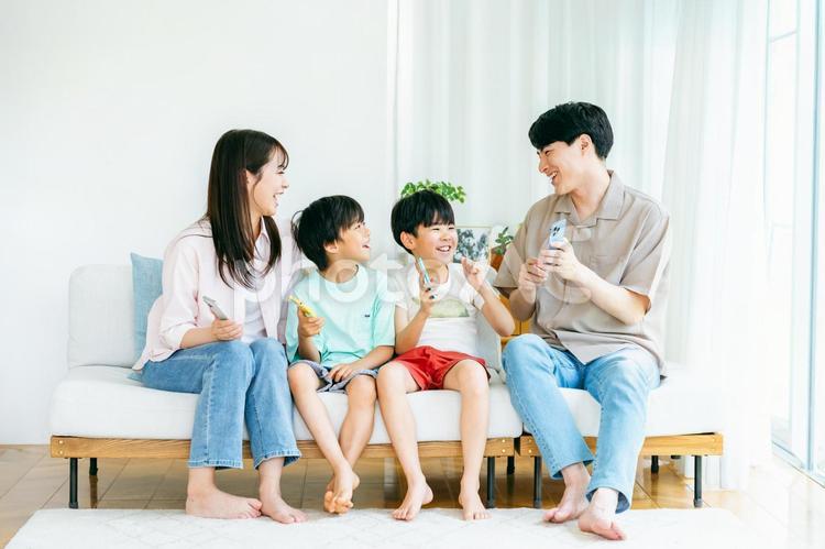スマホを持ってソファに座る家族 家族,スマホ,笑顔の写真素材