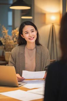 書類を広げ、笑顔で話すビジネスウーマン 書類を広げ、笑顔で話すビジネスウーマンの写真
