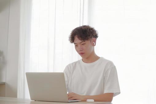 リビングでパソコン作業をする若い男性 リビングでパソコン作業をする若い男性 考える,悩む,真剣の写真素材