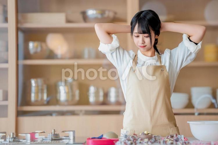 髪の毛を後ろに束ねるエプロン姿の女性 バレンタイン,バレンタインデー,チョコの写真素材