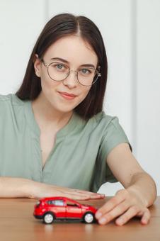 赤い車の模型にふれる女性スタッフ 保険業,事務職,接客業の写真素材