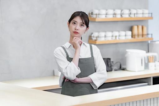 考えるエプロンをつけたスタッフ 考えるエプロンをつけたスタッフ カフェ,店員,接客の写真素材
