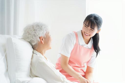 寝ているシニア女性を介護をする介護士 寝ているシニア女性を介護をする介護士 介護,介護士,シニアの写真素材