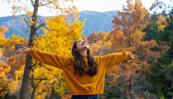 紅葉の中で深呼吸する秋服の日本人女性 紅葉の中で深呼吸する秋服の日本人女性の写真