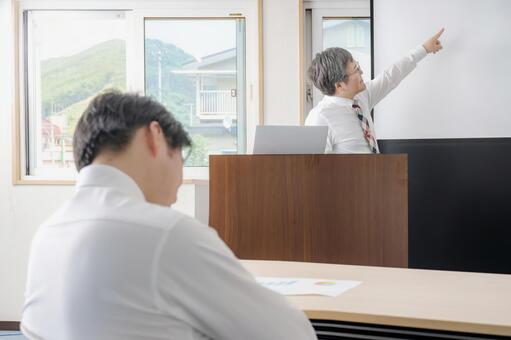 会議するビジネスマンと寝るビジネスマン 講義,研修,セミナーの写真素材