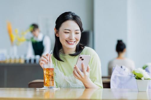 カフェでスマホを見る若い女性 カフェでスマホを見る若い女性 女性,カフェ,笑顔の写真素材
