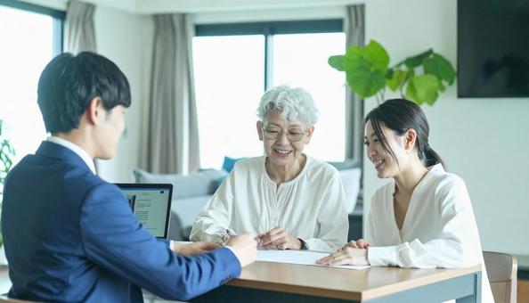 男性営業マンの説明を聞く親子 男性営業マンの説明を聞く親子の写真