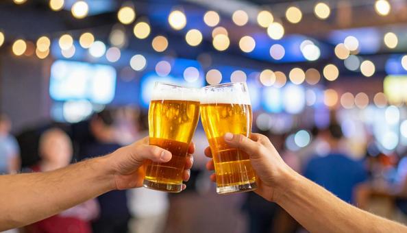 グラスビールで乾杯する男性2人の手元 グラスビールで乾杯する男性2人の手元の写真