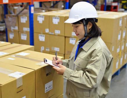 倉庫で在庫をチェックする女性作業員 倉庫で在庫をチェックする女性作業員の写真