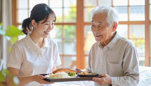 高齢男性と女性介護士の穏やかな食事風景 高齢男性と女性介護士の穏やかな食事風景の写真