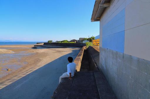海辺の駅　座って海を眺める男の子 海,空,青空の写真素材