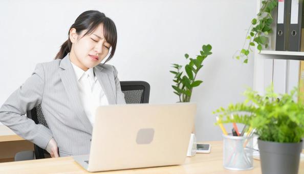 デスクワーク中に腰痛に悩むビジネスマン デスクワーク中に腰痛に悩むビジネスマンの写真