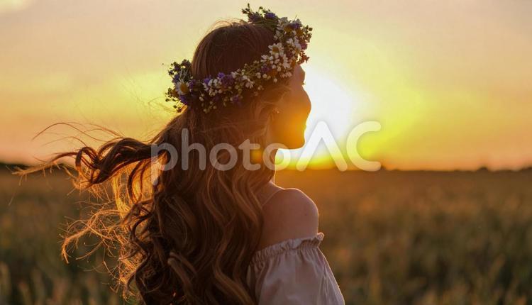 花輪のティアラをつけた女性が夕日に佇む 女性,花冠,花輪の写真素材