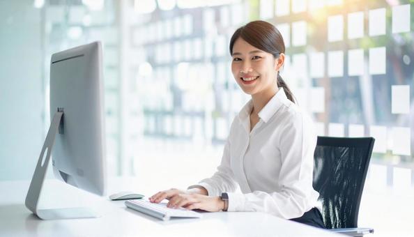 パソコンで仕事する白い服装の女性会社員 パソコンで仕事する白い服装の女性会社員の写真