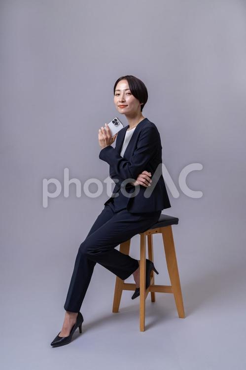 椅子に座り携帯を持つスーツを着た女性 ビジネスウーマン,転職,営業の写真素材