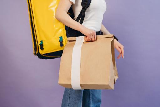 紙袋を持っている横向きのフードデリバリーの女性の写真