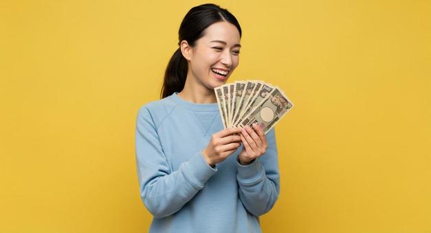 大金を手にして喜ぶ女性 大金を手にして喜ぶ女性の写真
